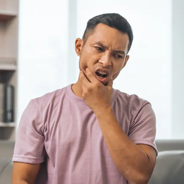 Young man holding his jaw in pain