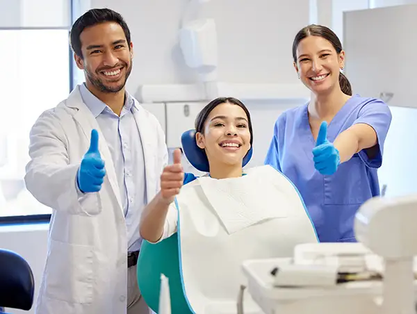 Woman, dentist, and hygienist giving the thumbs up after receiving dental exam at Avery Dental Center 