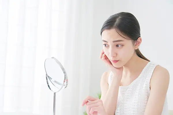 Woman looking in mirror concerned about oral cancer before her visit to Avery Dental Center 