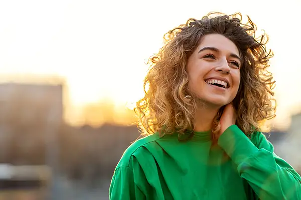 Young woman smiling freely with sun in the background